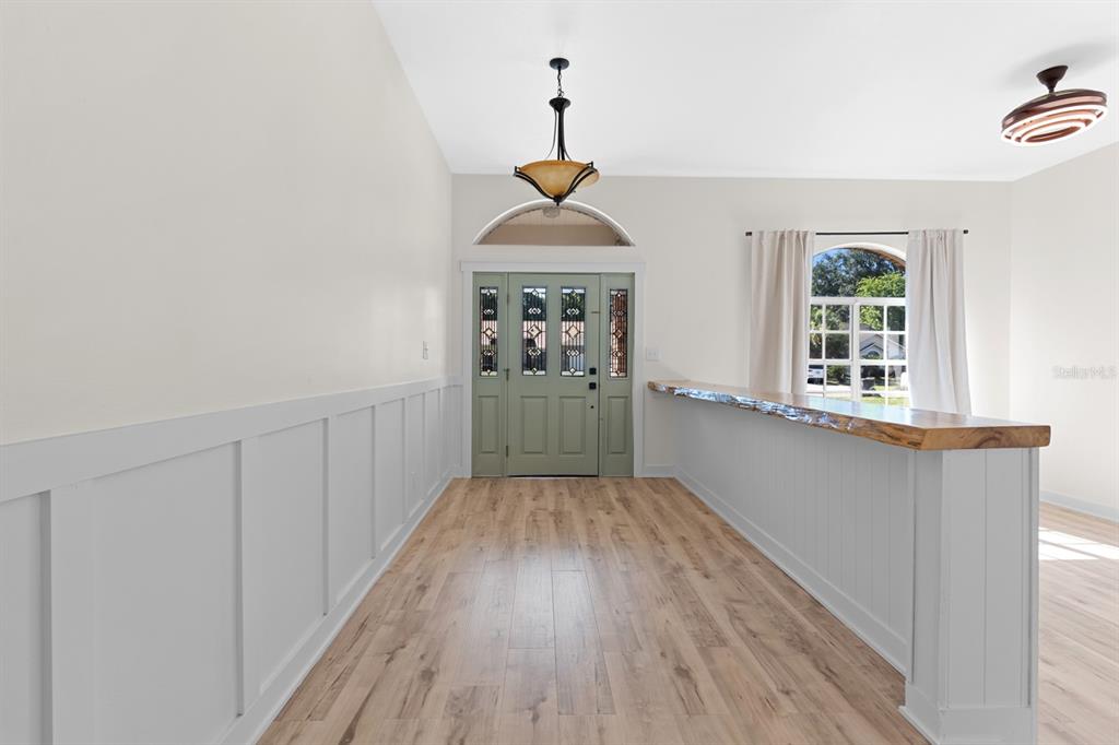 An entryway features light wood flooring, white wainscoting, a green front door, and a live-edge counter — 512 CAULDER PARK ROAD, SEFFNER, FL