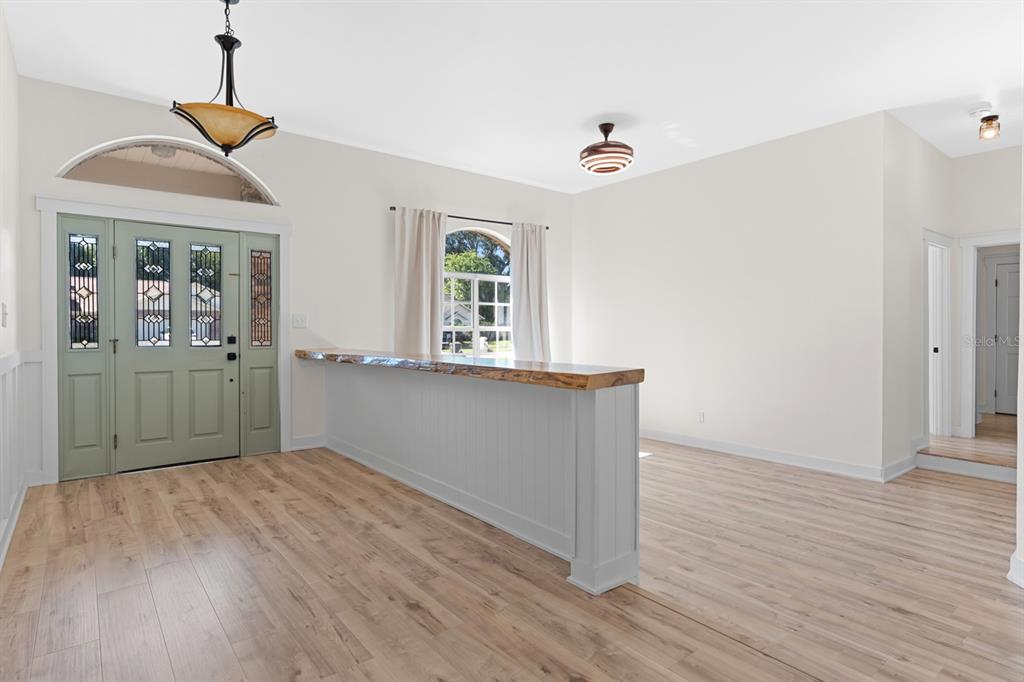 An interior view shows a light-filled room with wood flooring, a live-edge bar, and doors — 512 CAULDER PARK ROAD, SEFFNER, FL