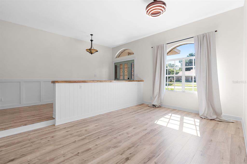 A room with light wood flooring, a half-wall partition, and a large arched window — 512 CAULDER PARK ROAD, SEFFNER, FL