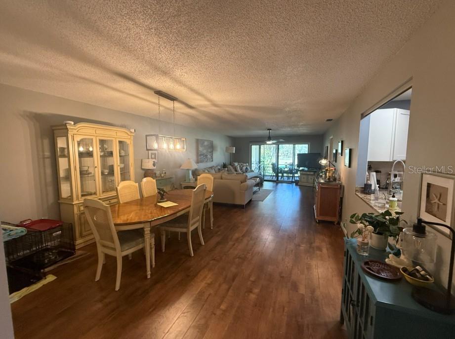 An open-concept dining and living area features wood-look flooring, a hutch, and sliding glass doors — 3500 EL CONQUISTADOR PARKWAY UNIT 124, BRADENTON, FL