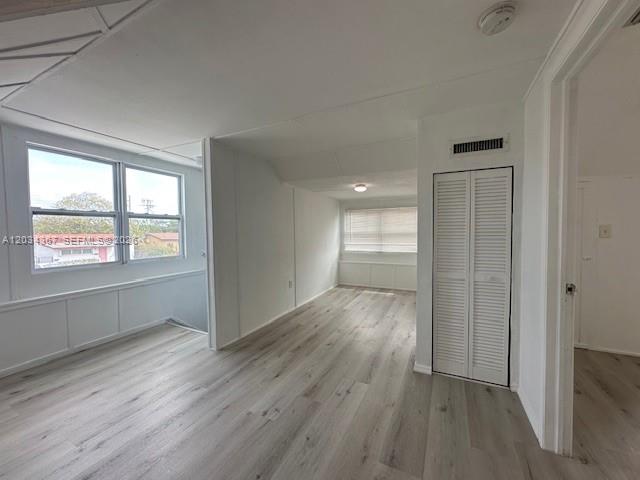 An interior view of a room with light wood-look flooring and white louvered closet doors — 274 E 9th St # 4, Hialeah FL 33010, HIALEAH, FL