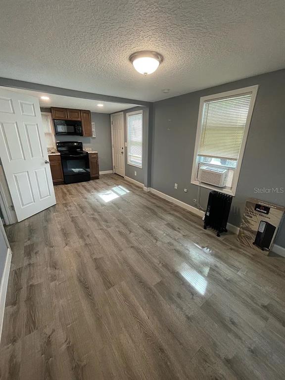 A room with gray walls, wood-look flooring, and an open kitchen area in the background — 1020 W PORTAGE STREET UNIT C, KISSIMMEE, FL