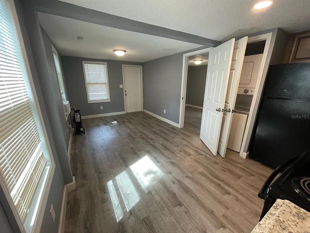 A room with gray walls, wood-look flooring, a laundry closet, and a doorway to another room — 1020 W PORTAGE STREET UNIT C, KISSIMMEE, FL