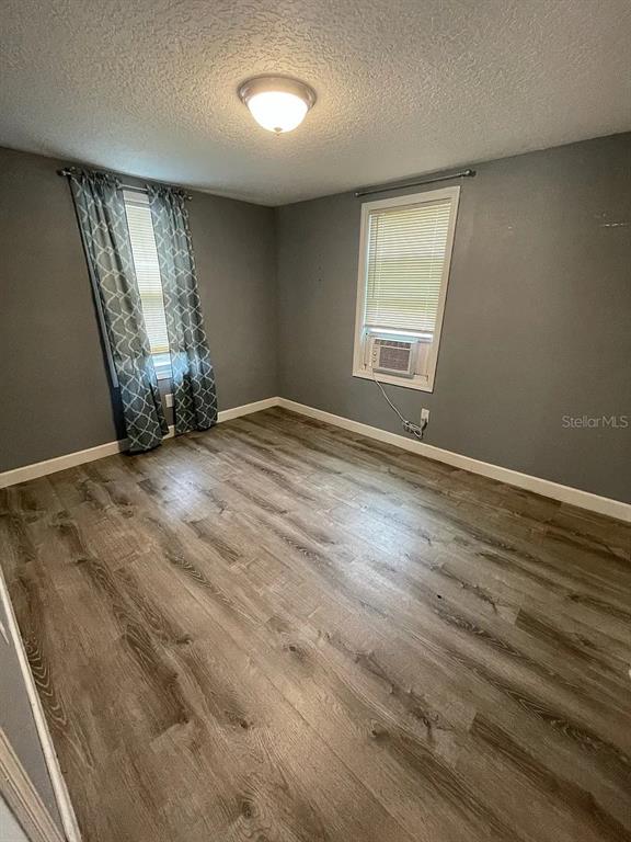 An empty bedroom features gray walls, wood-look flooring, a ceiling light, and two windows — 1020 W PORTAGE STREET UNIT C, KISSIMMEE, FL
