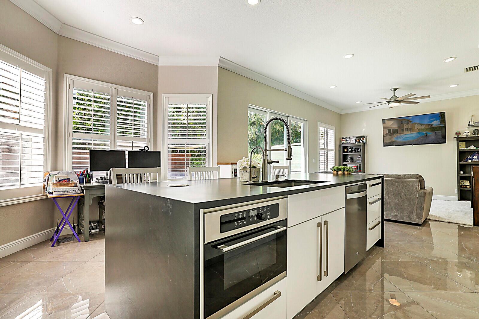 A modern kitchen features white lower cabinets, dark gray upper cabinets, and a stainless steel stove — 7167 Ivy Crossing Lane, Boynton Beach FL 33436, BOYNTON BEACH, FL