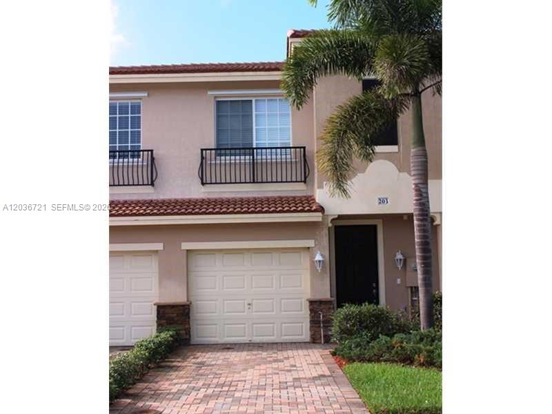 A two-story townhouse features a beige stucco exterior, a garage, and a small balcony — SUNRISE, FL