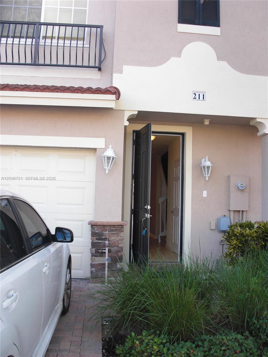 The exterior of a two-story townhouse features a white garage, a black front door, and a balcony — SUNRISE, FL