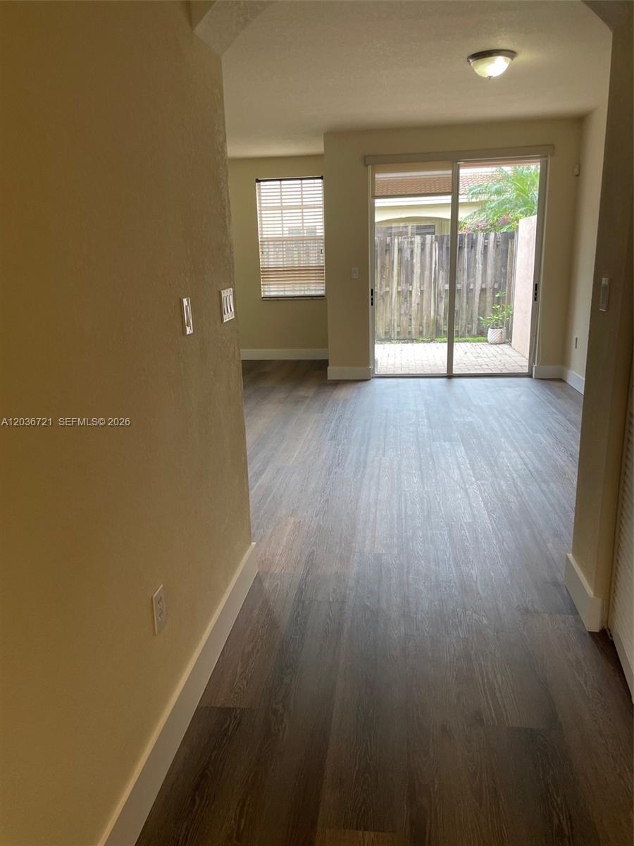 An interior view shows a living area with wood-look flooring and a sliding glass door — SUNRISE, FL
