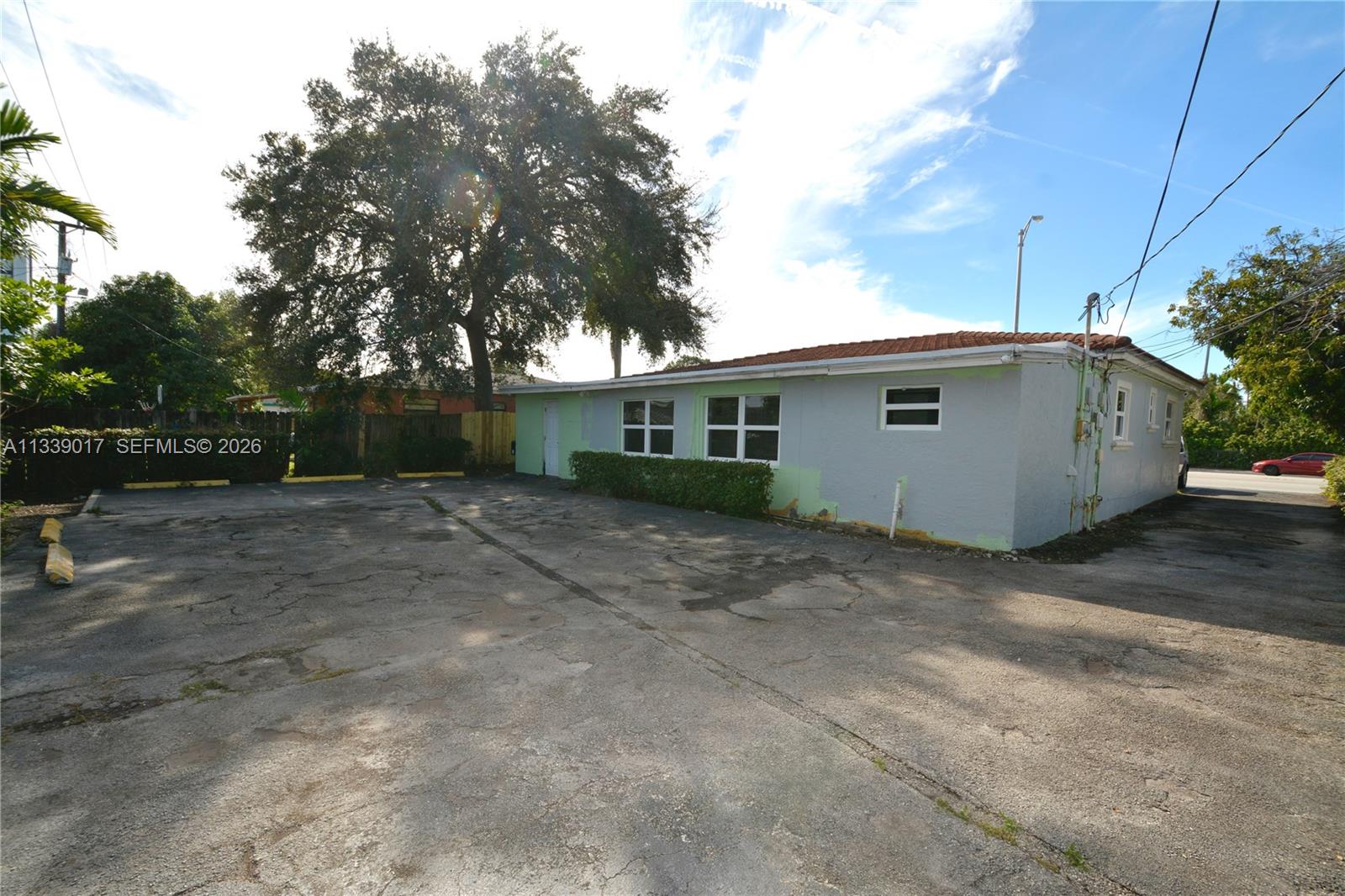 A single-story gray building with a paved parking lot and a large tree — 16921 NE 6th Ave, North Miami Beach FL 33162, NORTH MIAMI BEACH, FL