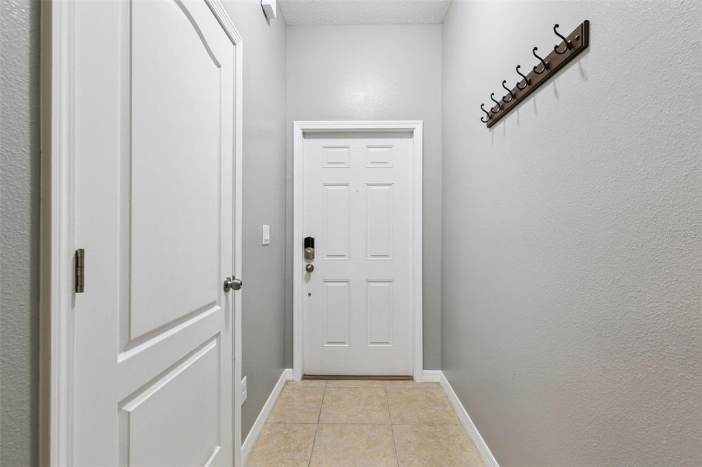 A small entryway features light gray walls, tiled flooring, a white door, and wall-mounted hooks — 1250 TWIN TREES LANE, SANFORD, FL