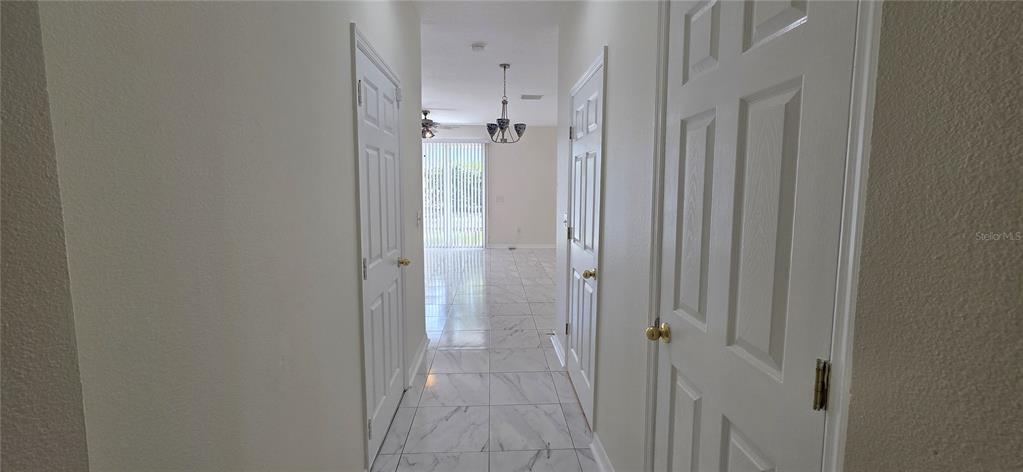 A hallway with white doors and tiled floors leads to a room with sliding doors — 2027 STRATHMILL DRIVE, CLEARWATER, FL