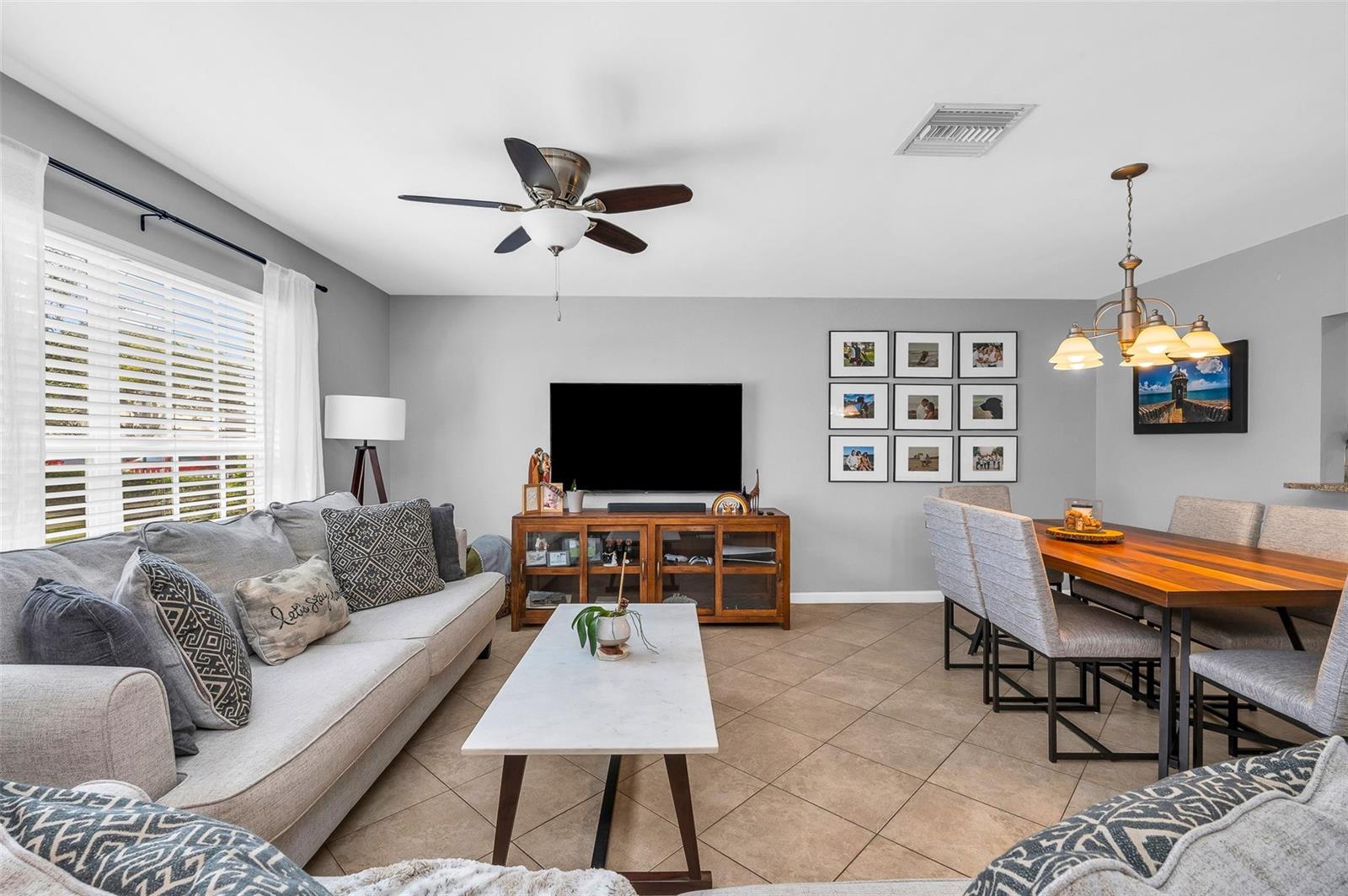 A living and dining area features a grey sofa, television console, and wooden dining table — 3860 NW 122nd Terrace, Sunrise FL 33323, SUNRISE, FL