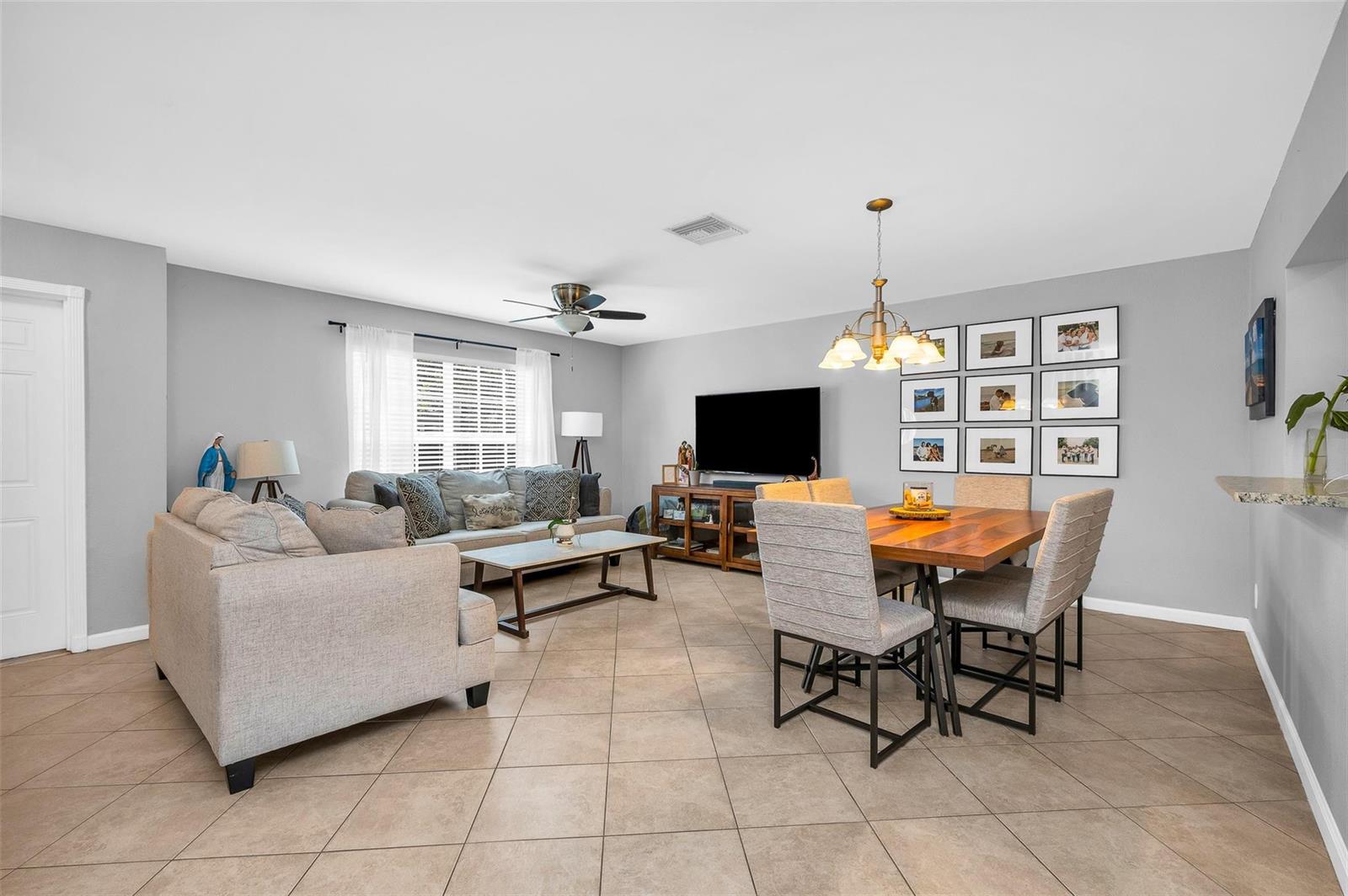 An open-concept living and dining room features tile flooring, neutral walls, and a ceiling fan — 3860 NW 122nd Terrace, Sunrise FL 33323, SUNRISE, FL