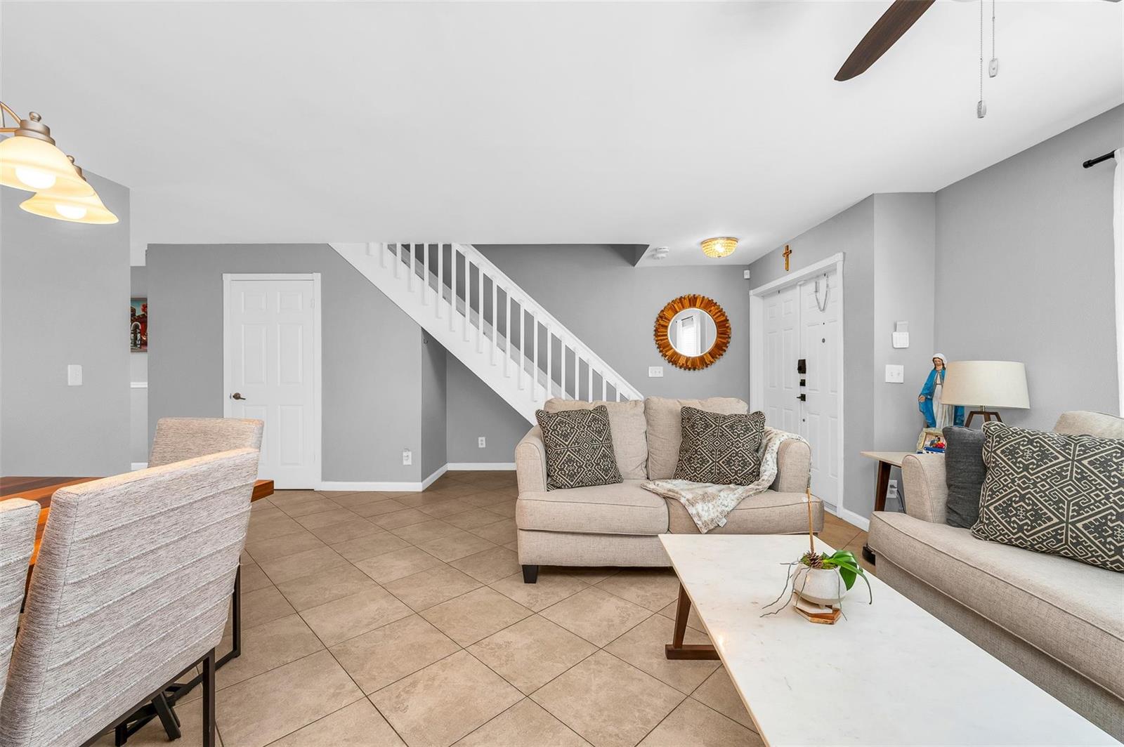 A living room with tile floors, a staircase, and two beige sofas facing a table — 3860 NW 122nd Terrace, Sunrise FL 33323, SUNRISE, FL