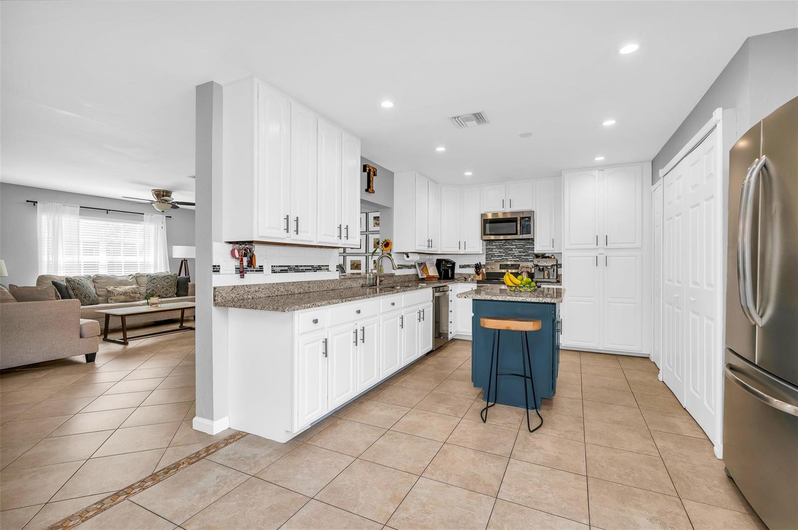 A kitchen with white cabinets, granite countertops, a blue island, and tile flooring — 3860 NW 122nd Terrace, Sunrise FL 33323, SUNRISE, FL