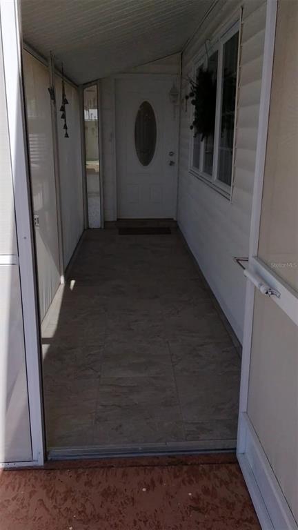 A covered entryway with tiled flooring leads to a white front door with an oval window — 702 CYPRESS PLACE, SUN CITY CENTER, FL