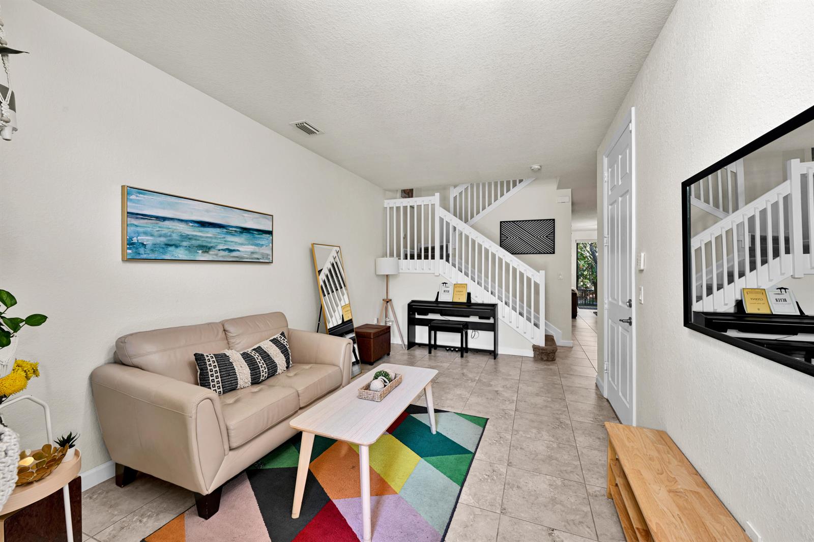 A living room features a beige sofa, a colorful rug, and a staircase with white railings — 6977 Broadland Way, Coconut Creek FL 33073, COCONUT CREEK, FL