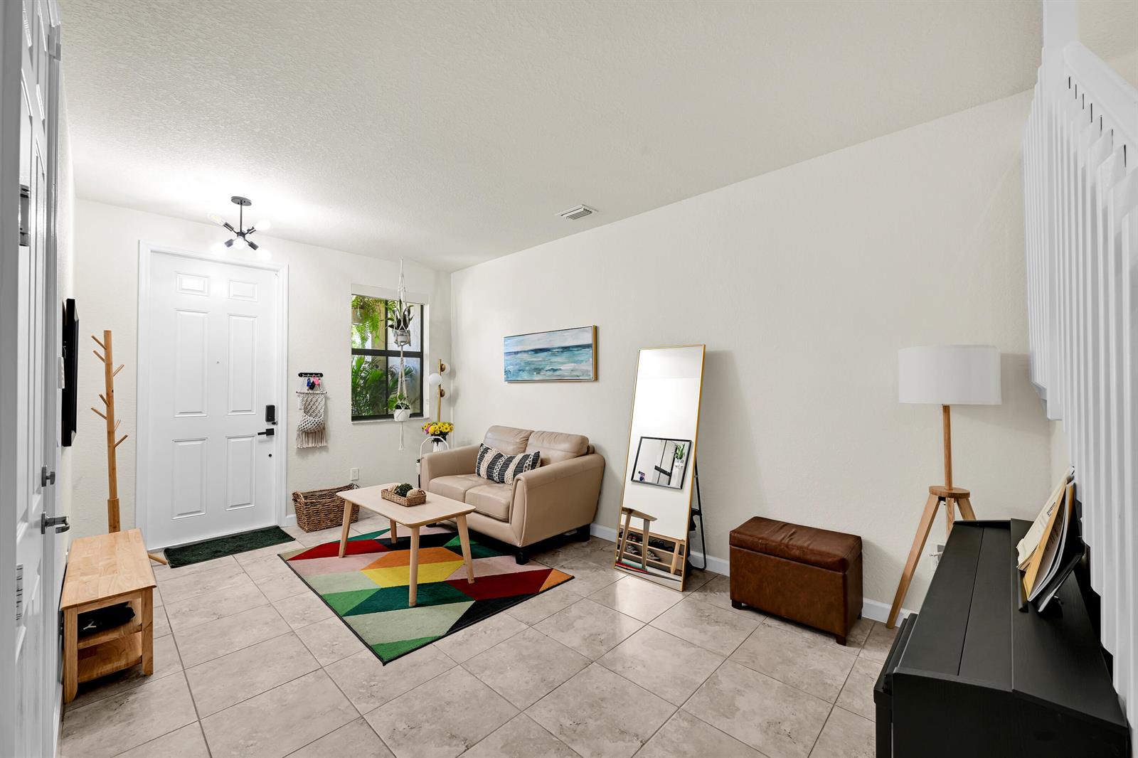 A living room with tile floors, a beige loveseat, a colorful rug, and a front door — 6977 Broadland Way, Coconut Creek FL 33073, COCONUT CREEK, FL