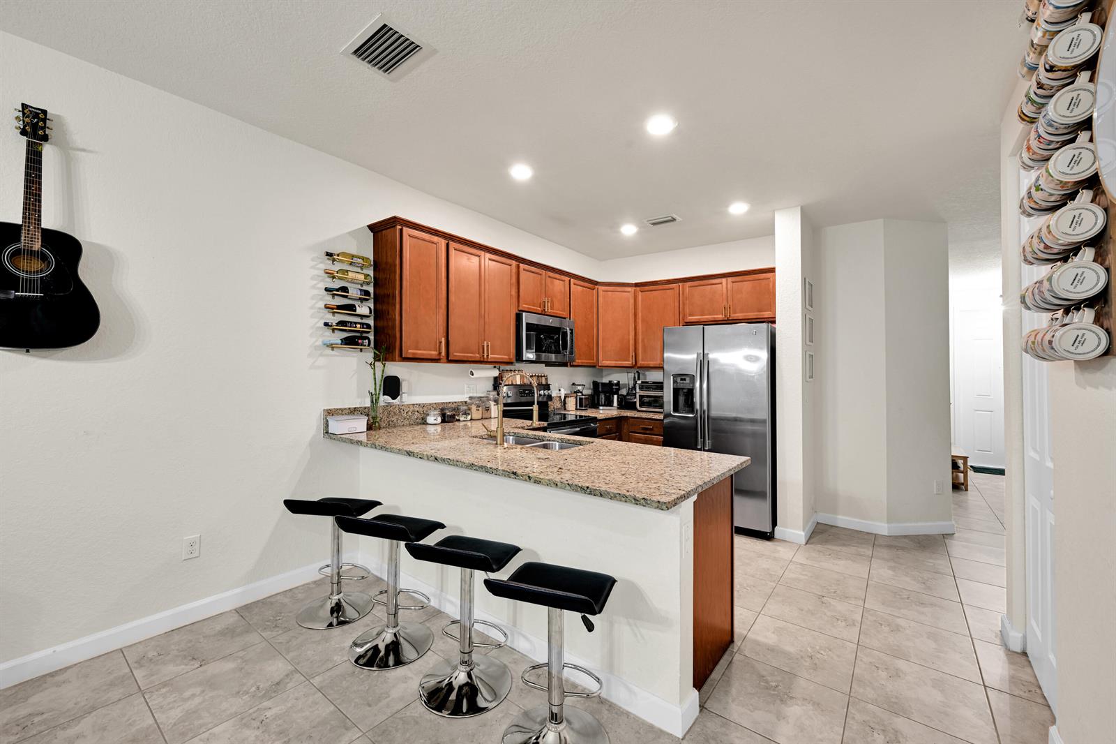 A kitchen features wood cabinets, granite countertops, stainless steel appliances, and a breakfast bar with stools — 6977 Broadland Way, Coconut Creek FL 33073, COCONUT CREEK, FL