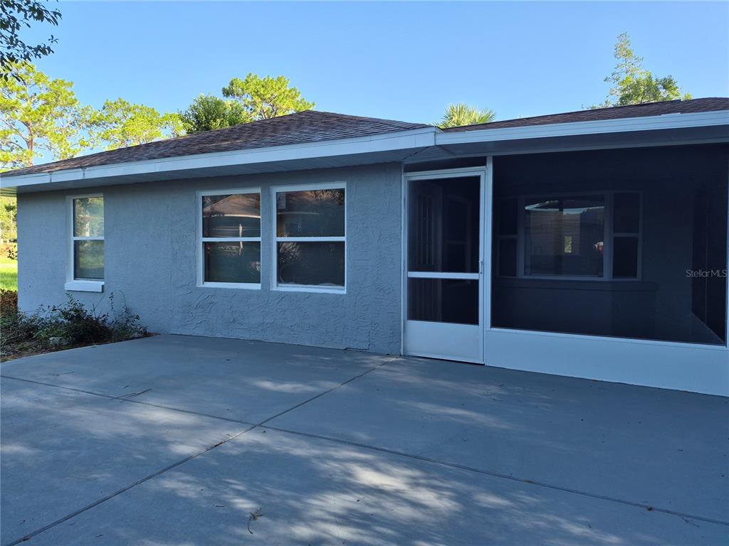 A gray house exterior features a screened-in porch and a concrete patio area — 1213 W SORRENTO DRIVE, CITRUS SPRINGS, FL