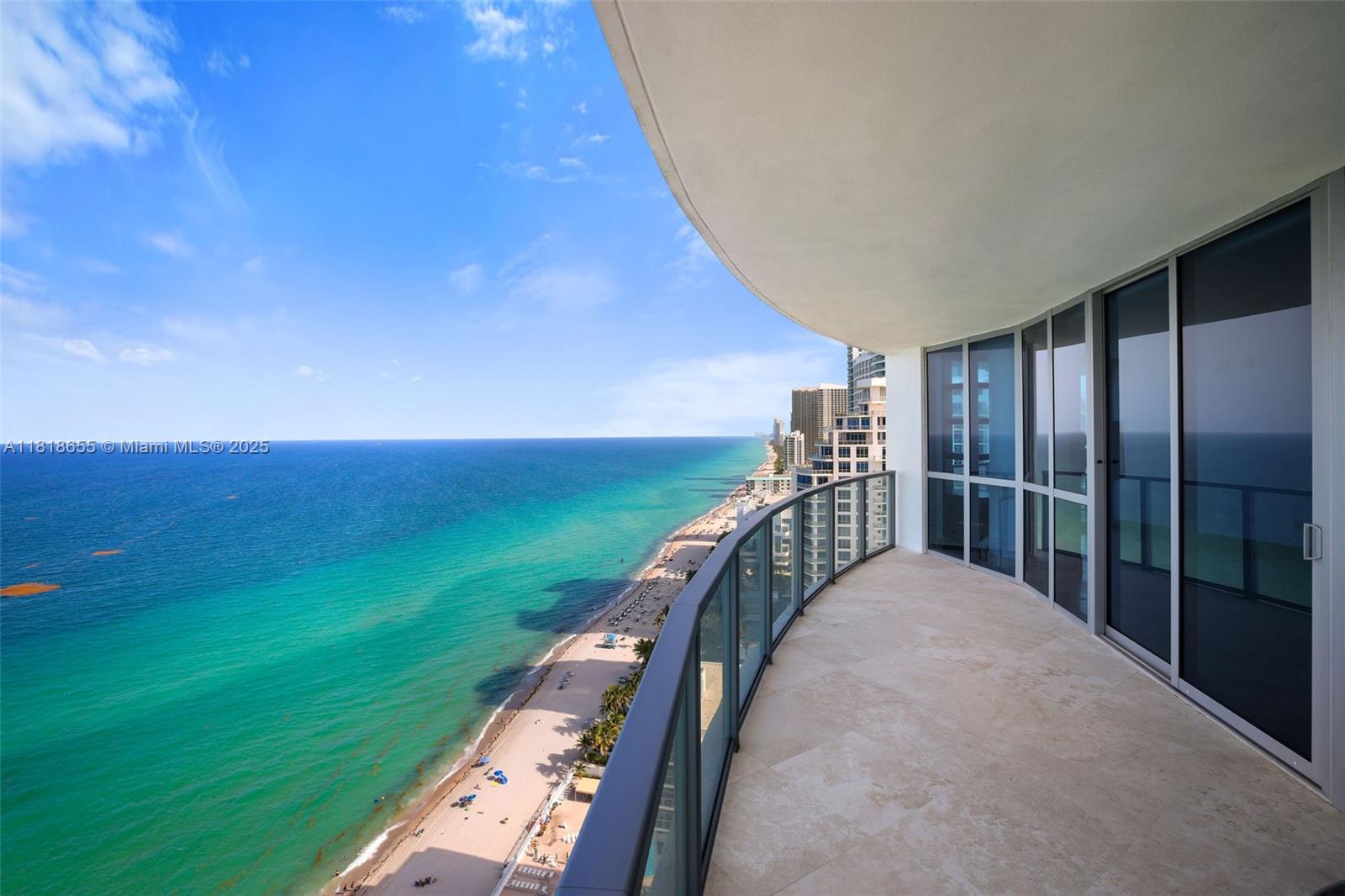 A curved balcony with glass railings overlooks a sandy beach and the ocean — 3101 S Ocean Dr # 2708, Hollywood FL 33019, HOLLYWOOD, FL