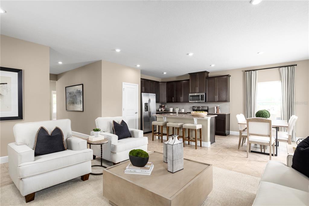 An open-concept kitchen and living area featuring dark cabinetry, a central island, and neutral furniture — 378 HAMMOCK OAKS BOULEVARD, LADY LAKE, FL