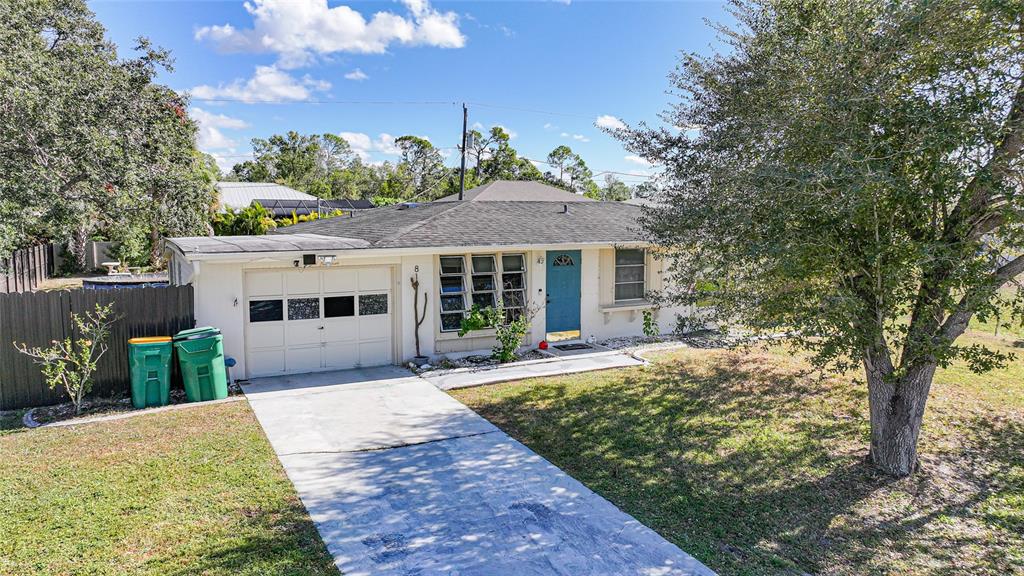 A single-story house with a white exterior, a blue front door, and a concrete driveway — 819 HALEYBURY STREET NW, PORT CHARLOTTE, FL