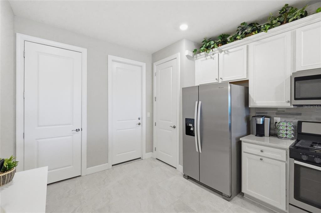 A kitchen features white cabinets, stainless steel appliances, light gray walls, and tile flooring — 14571 MOSSY PINE COURT, NOKOMIS, FL