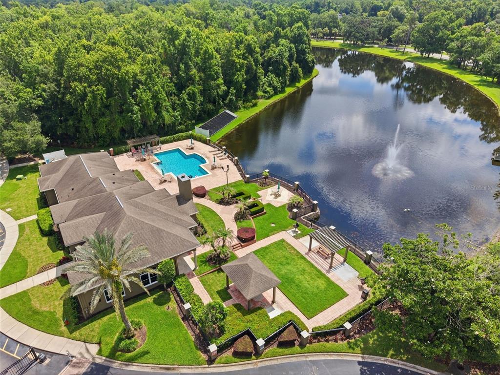 An aerial view shows a clubhouse with a swimming pool, gazebo, and a large pond — 420 SUMMIT RIDGE PLACE UNIT 300, LONGWOOD, FL