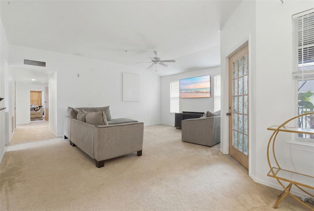 A living room with beige carpet, white walls, a gray sectional, and a glass-paneled door — 420 SUMMIT RIDGE PLACE UNIT 300, LONGWOOD, FL