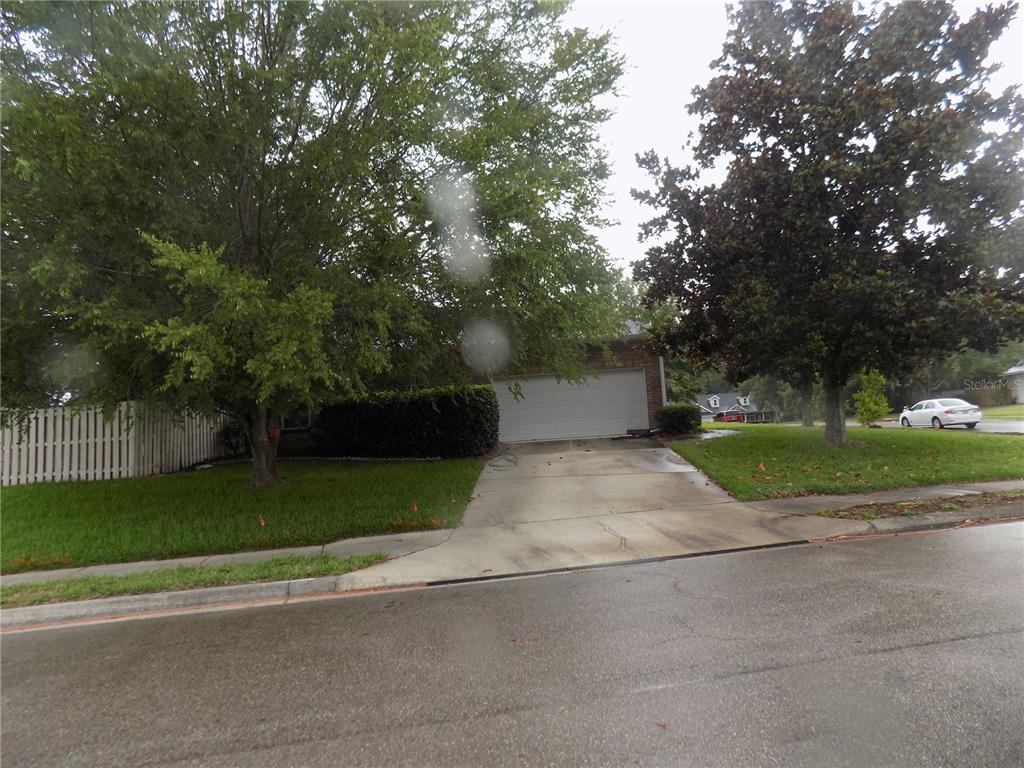 A residential house exterior features a concrete driveway leading to a two-car garage — 11903 NW 9TH ROAD, GAINESVILLE, FL