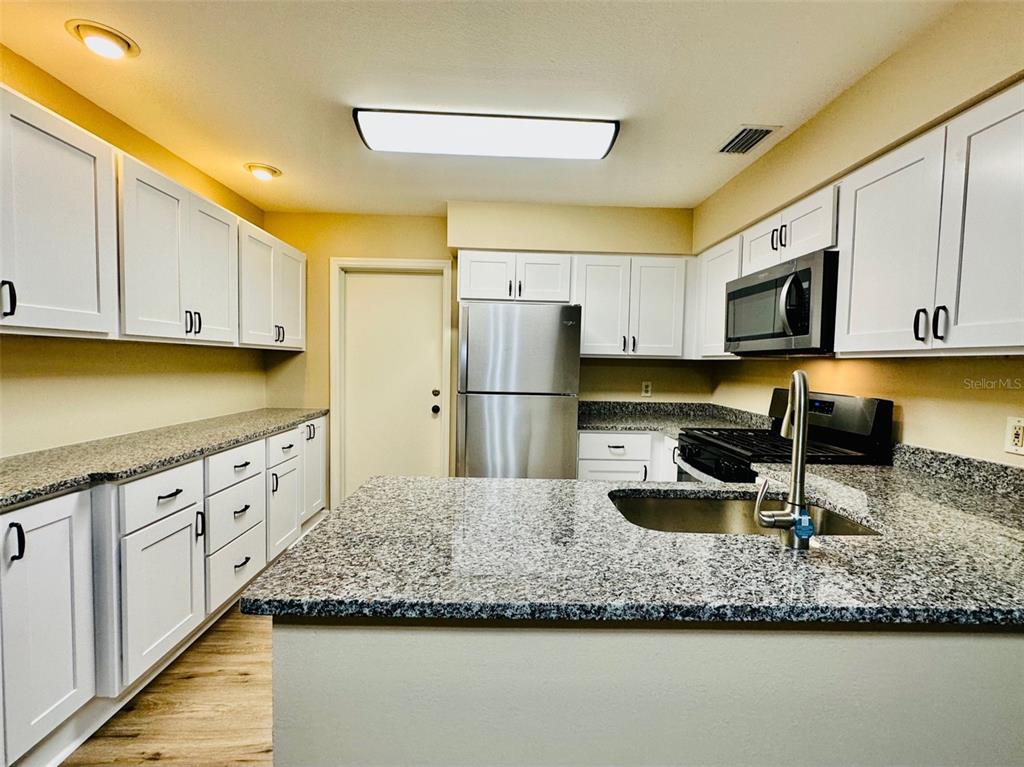 A kitchen features white cabinets, granite countertops, stainless steel appliances, and a central island — 15082 SW 38TH CIRCLE, OCALA, FL