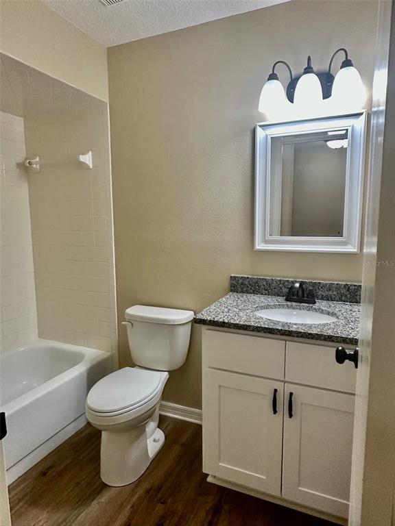 A bathroom features a white vanity with a granite countertop, a toilet, and a bathtub — 15082 SW 38TH CIRCLE, OCALA, FL
