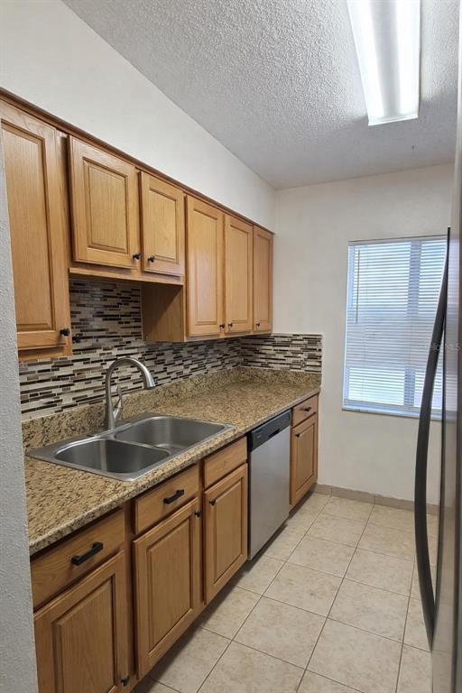 A kitchen features oak cabinets, granite countertops, a stainless steel sink, and a tiled backsplash — 7516 NEEDLE LEAF PLACE UNIT 43, TAMPA, FL