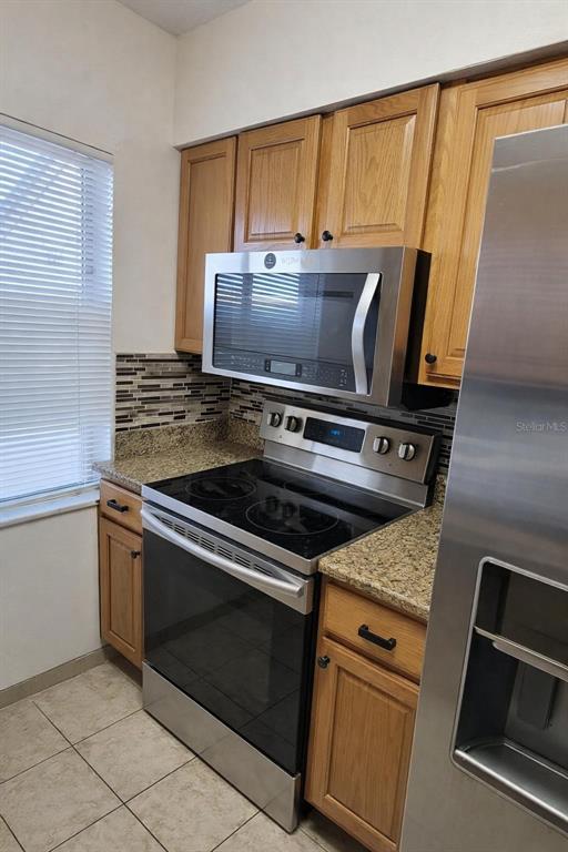 A kitchen features wooden cabinets, granite countertops, and stainless steel appliances — 7516 NEEDLE LEAF PLACE UNIT 43, TAMPA, FL