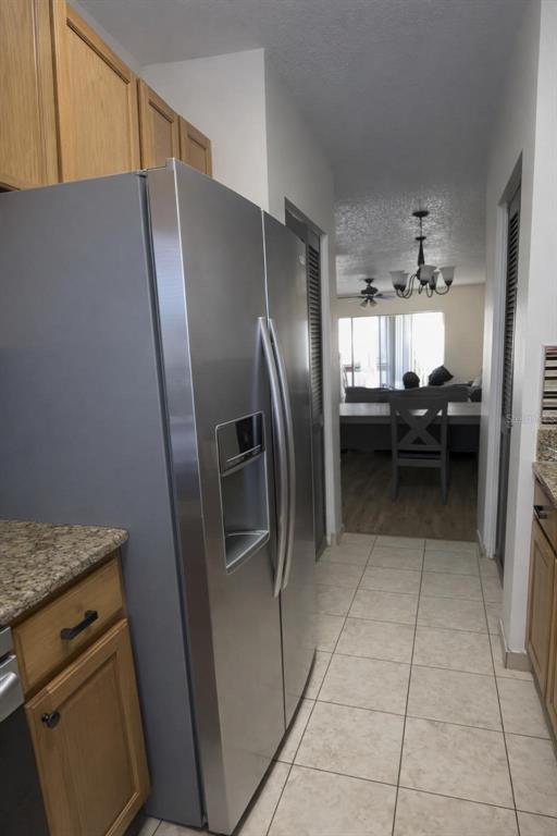 A stainless steel refrigerator stands in a kitchen with light wood cabinets and tile flooring — 7516 NEEDLE LEAF PLACE UNIT 43, TAMPA, FL