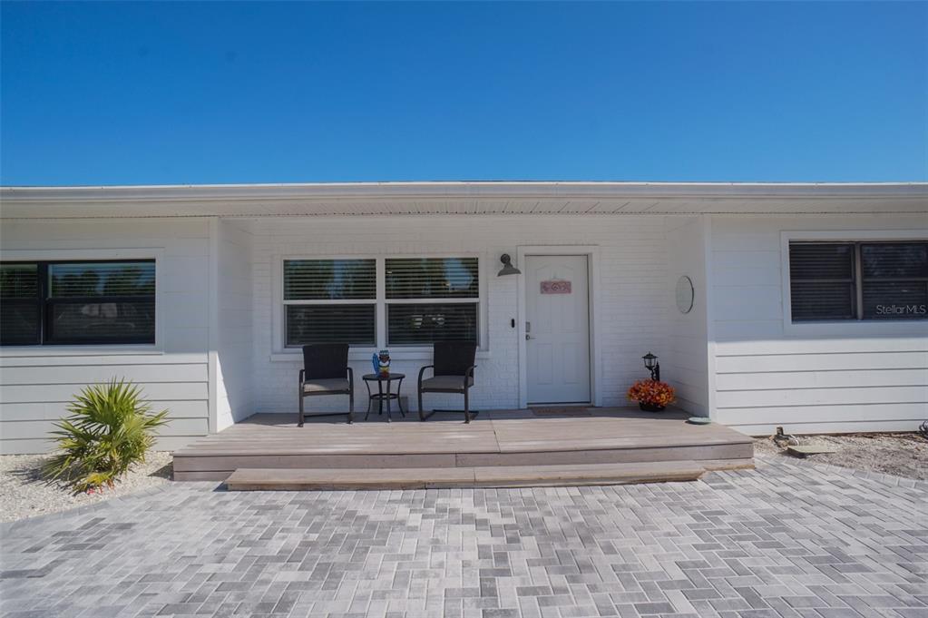 A white house exterior features a wooden porch, two chairs, and a paved driveway — 929 LANTANA AVENUE, CLEARWATER BEACH, FL