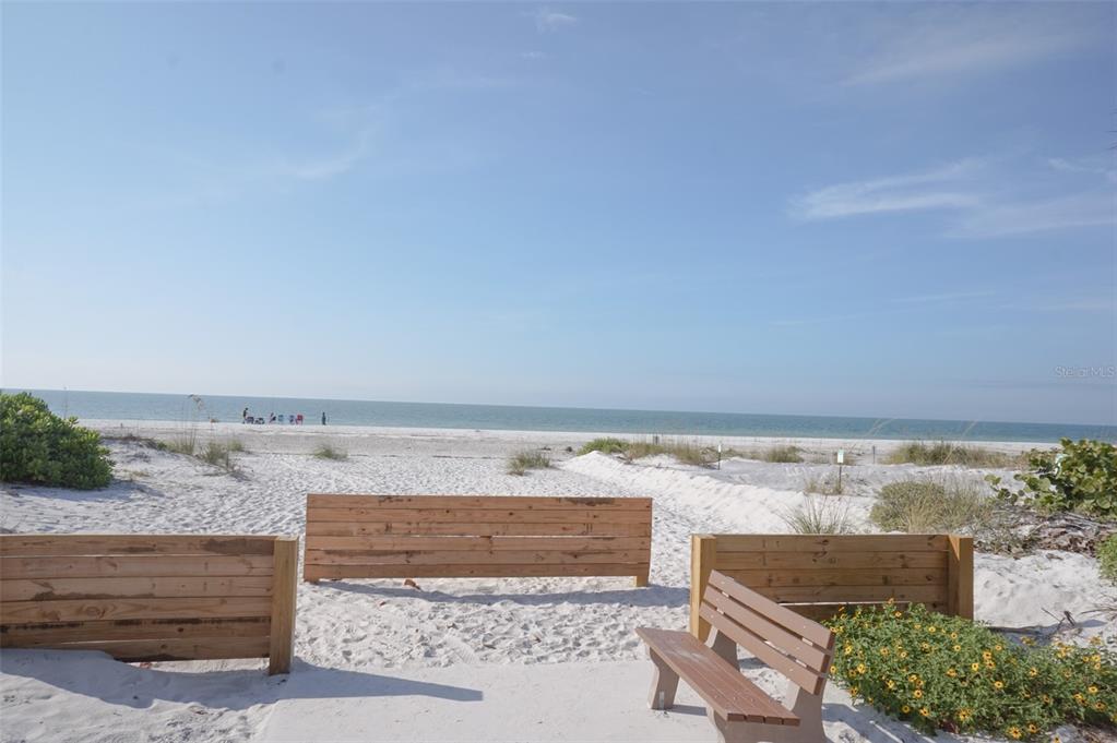 A wooden bench sits on a sandy path leading to a beach with ocean views — 929 LANTANA AVENUE, CLEARWATER BEACH, FL