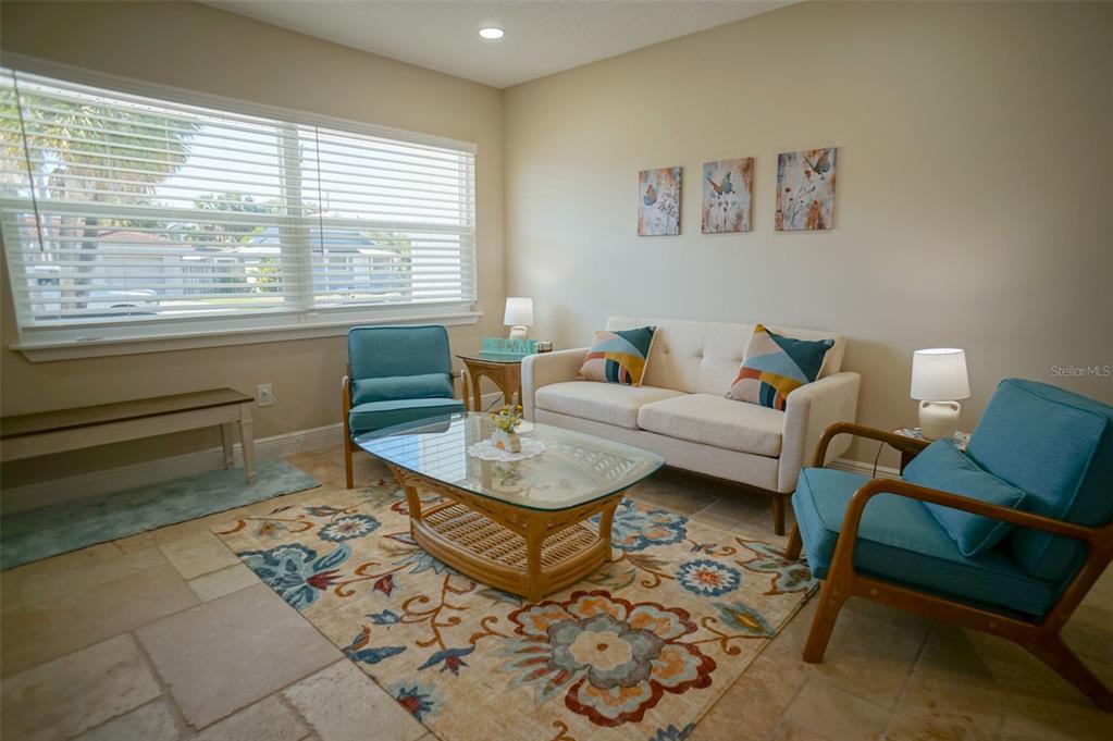 A living room features a beige sofa, two teal armchairs, and a glass-topped coffee table — 929 LANTANA AVENUE, CLEARWATER BEACH, FL