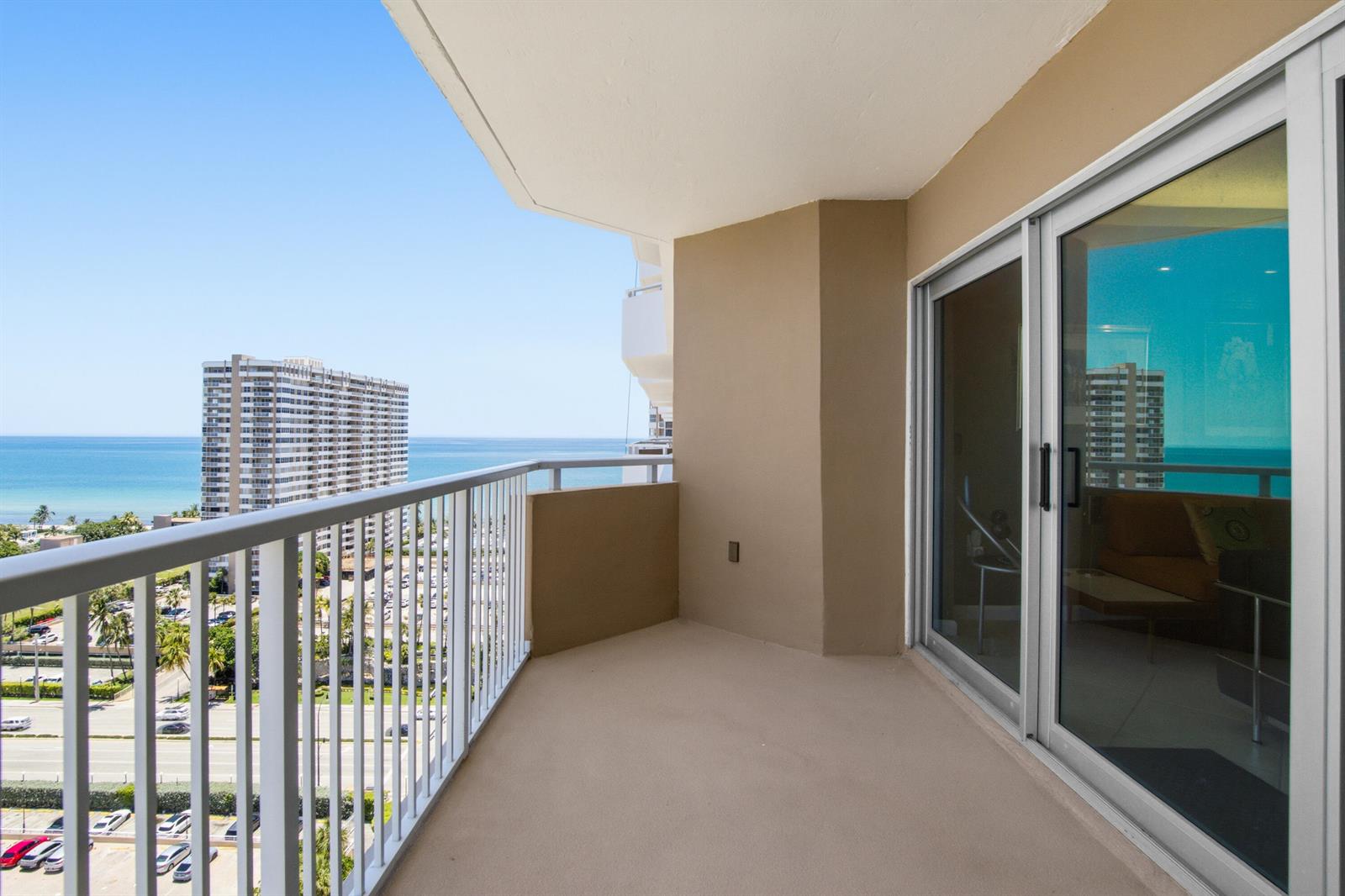 A balcony with white railings overlooks a coastal street and the ocean — 1985 S Ocean Drive # 17d, Hallandale Beach FL 33009, HALLANDALE BEACH, FL