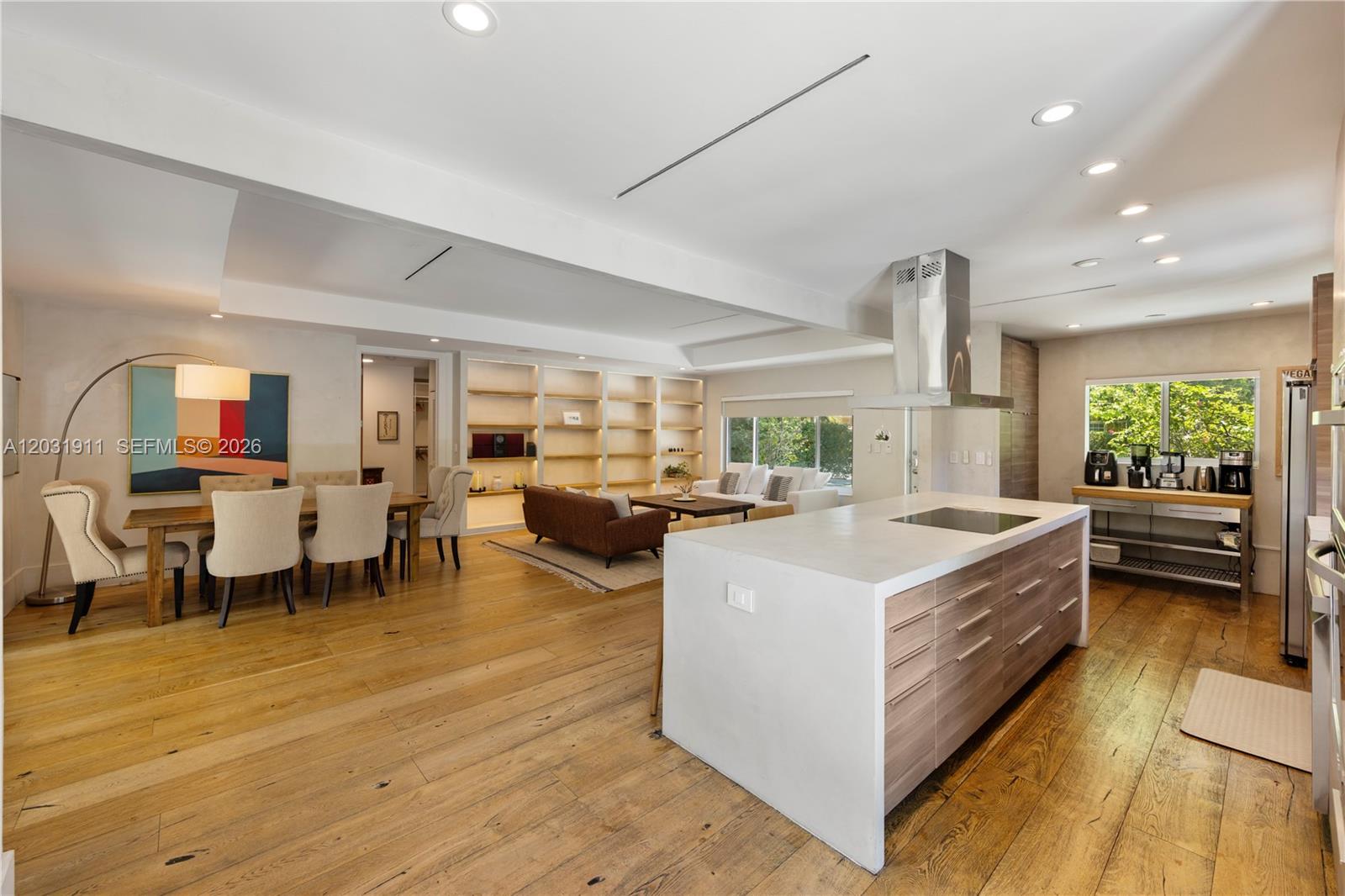 An open-concept living area features a kitchen island, dining space, and built-in shelving — 651 NE 52nd Ter, Miami FL 33137, MIAMI, FL