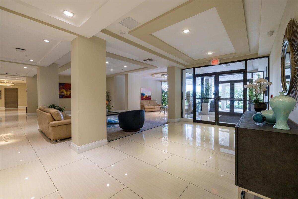A modern lobby features white tile floors, recessed lighting, and a glass-paned entrance door — 3912 S Ocean Boulevard # 1211, Highland Beach FL 33487, HIGHLAND BEACH, FL