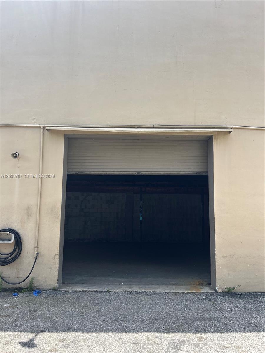 A beige exterior wall features a large, open roll-up metal bay door — 2309 SW 60th Way # B, Miramar FL 33023, MIRAMAR, FL