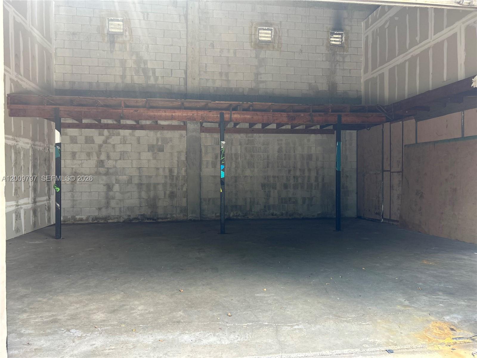An unfinished industrial space features a concrete floor, cinder block walls, and a wooden mezzanine — 2309 SW 60th Way # B, Miramar FL 33023, MIRAMAR, FL