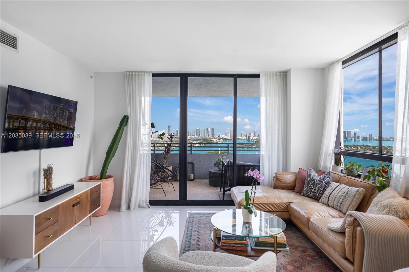 A living room with a leather sectional, glass coffee table, and balcony overlooking the city — 1330 West Ave # 3001, Miami Beach FL 33139, MIAMI BEACH, FL