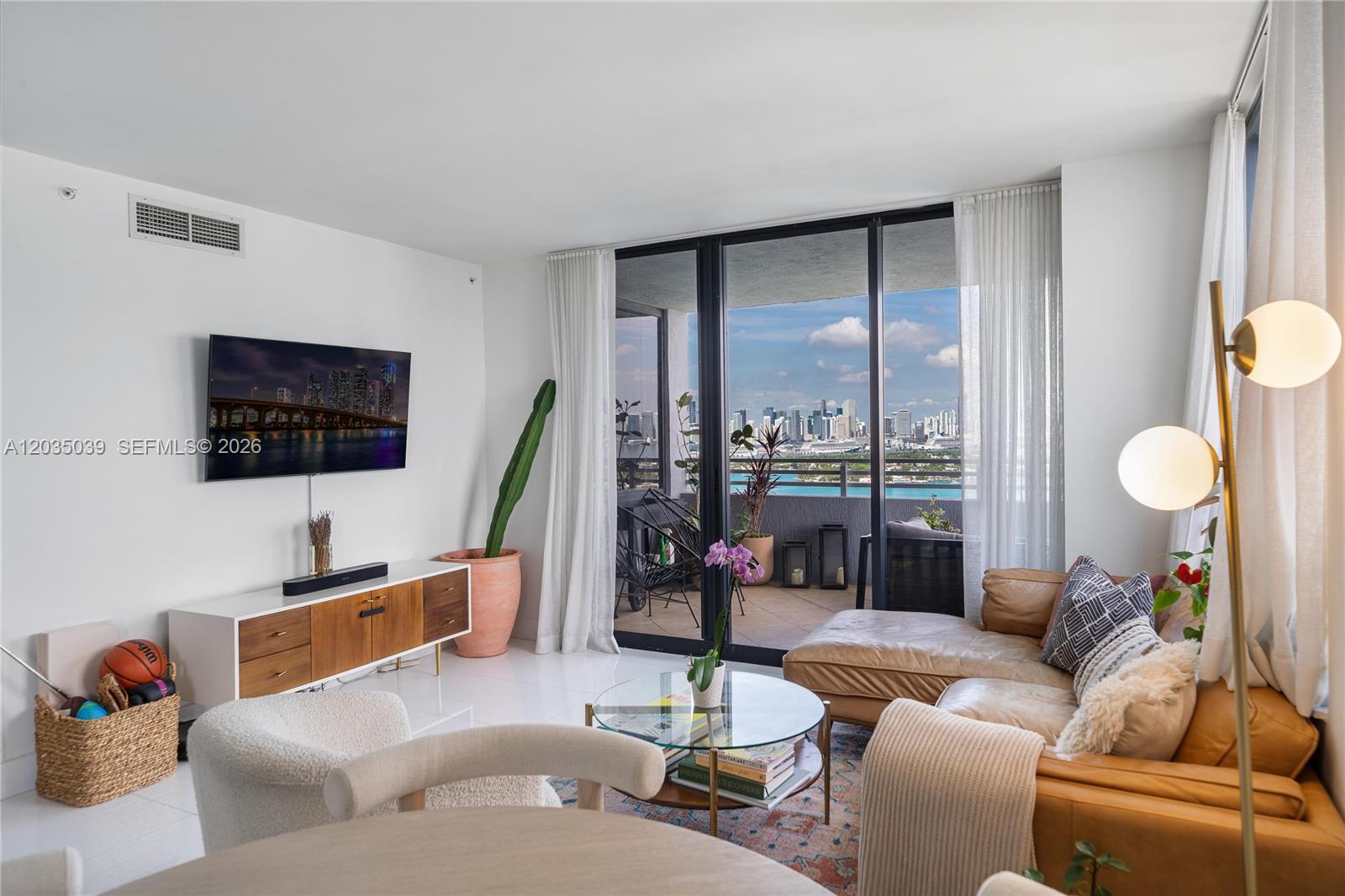 A living room features a tan leather sectional, a glass coffee table, and a balcony view — 1330 West Ave # 3001, Miami Beach FL 33139, MIAMI BEACH, FL