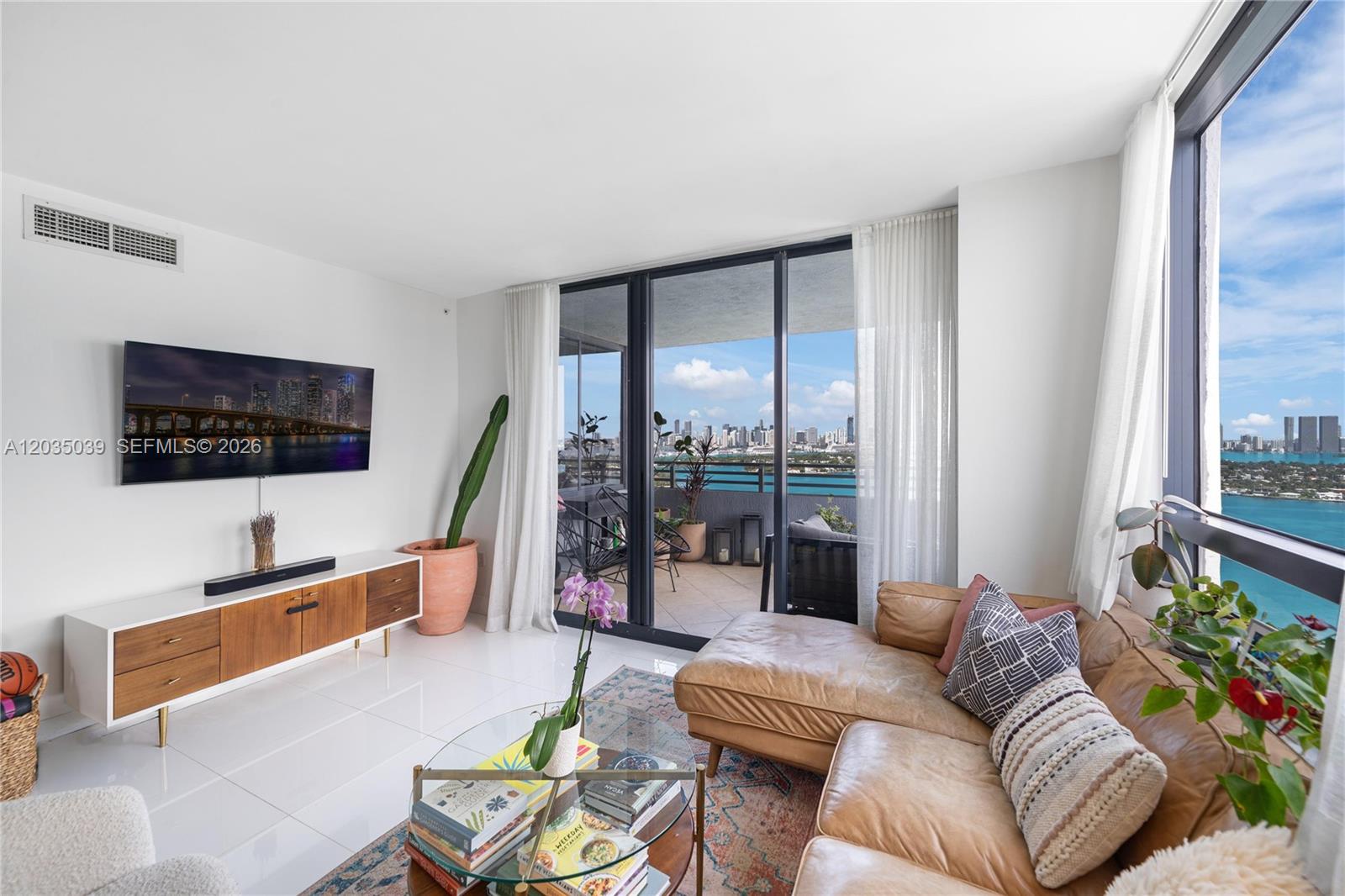 A bright living room features a leather sectional, glass coffee table, and balcony with water views — 1330 West Ave # 3001, Miami Beach FL 33139, MIAMI BEACH, FL