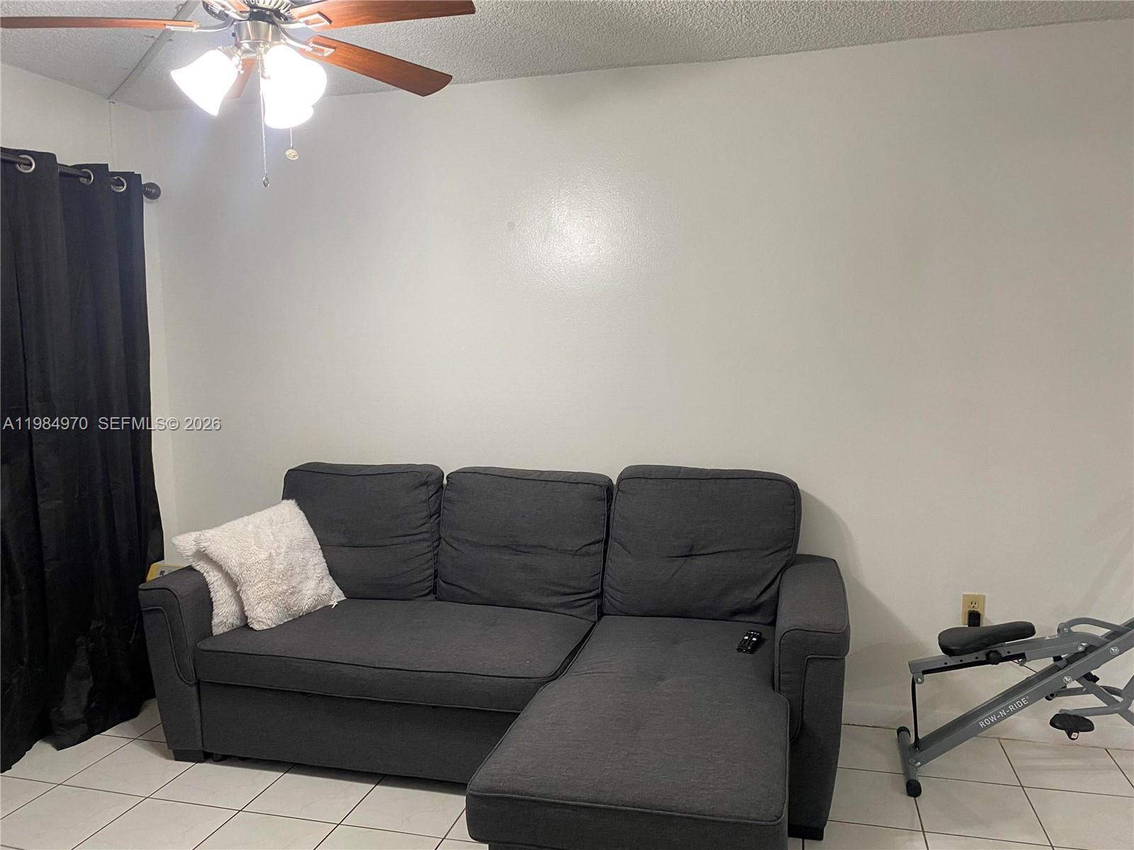 A living room features a gray sectional sofa, a ceiling fan, and tiled flooring — 9405 W Flagler St # D105, Miami FL 33174, MIAMI, FL