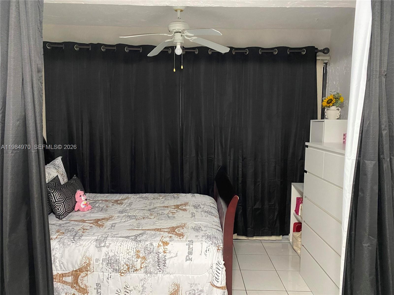 A bedroom features a bed with Paris-themed bedding, black curtains, and a white dresser — 9405 W Flagler St # D105, Miami FL 33174, MIAMI, FL