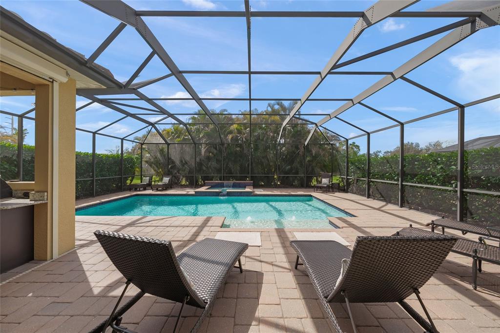 A screened-in patio features a swimming pool, a raised spa, and lounge chairs — 7809 PASSIONFLOWER DRIVE, SARASOTA, FL